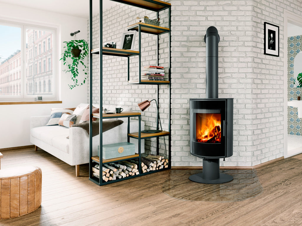 Soba metalica rotativa Laredo T 30 montata inntr-un living urban in stil industrial, pe un perete placat cu caramida gri deschis